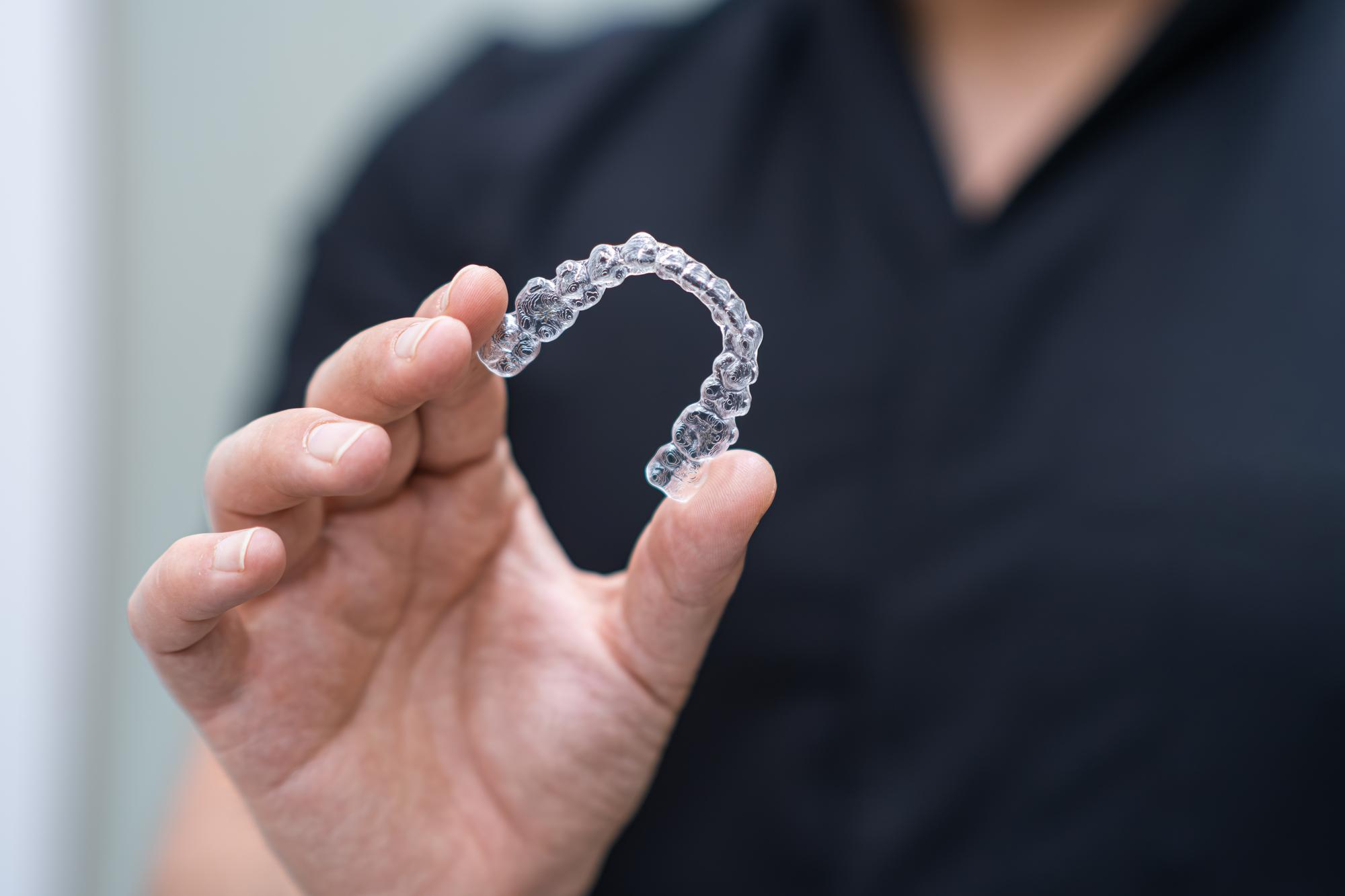 Patient holding a clear Invisalign aligner