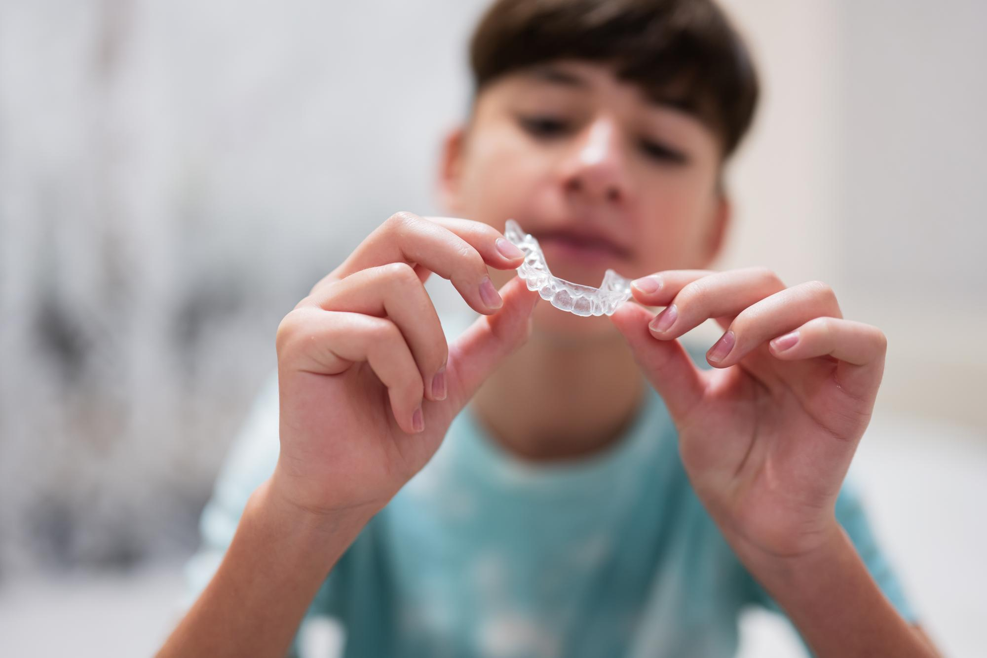 Teen holding a clear Invisalign aligner